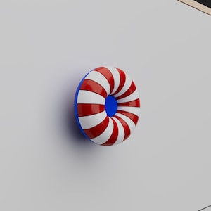 Peut inclure: Un bouton de meuble circulaire en forme de tore avec une finition brillante. La surface présente des rayures radiales alternées de couleur rouge vif et blanche. Le trou central du bouton est bordé d'une couleur bleue unie contrastante.