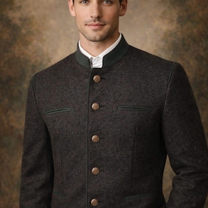 May include: A dark grey jacket with a mandarin collar, green trim, and gold buttons. The jacket is worn over a white shirt. The man in the image is looking at the camera.