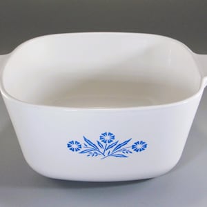 May include: White square casserole dish with two handles and a blue floral design. The dish is made of ceramic and is suitable for baking and serving. The dish measures approximately 9 inches wide.