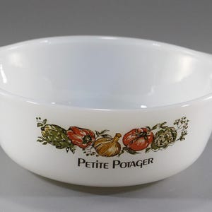 May include: White ceramic bowl with two handles, featuring a colorful vegetable design around the rim. The bowl has the words "Petite Potager" printed on the front. The vegetables include tomatoes, artichokes, and onions.