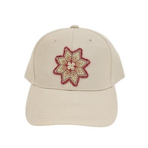 May include: A beige baseball cap with a floral design. The embroidered flower is in shades of red, beige, and light brown. The cap has a curved brim and a button on top. This hat is a stylish accessory.