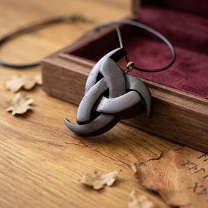 May include: A white ceramic mug with a black handle and the text "But First, Coffee" in a black, bold font. The mug is on a wooden surface.