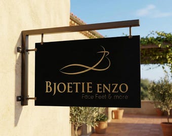 Peut inclure: Une enseigne rectangulaire noire avec le texte "BJOETIE ENZO Face Feet & more" en lettres dorées, suspendue à un support en métal marron. L'enseigne présente un design doré stylisé. L'enseigne est fixée sur un mur beige.
