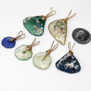 Puede incluir: Seis colgantes de vidrio marino en varias formas y colores, incluyendo azul, verde y transparente. Cada colgante est&aacute; envuelto con alambre dorado y tiene un lazo para un collar. Se incluye una moneda como referencia de tama&ntilde;o.