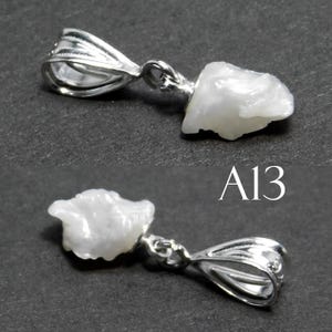 May include: A white pearl pendant with a silver bail. The pearl is irregularly shaped and has a rough texture. The pendant is labeled "A13".
