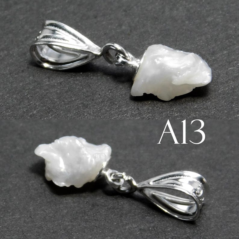 May include: A white pearl pendant with a silver bail. The pearl is irregularly shaped and has a rough texture. The pendant is labeled "A13".