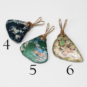 Puede incluir: Tres colgantes hechos de vidrio antiguo, cada uno con una forma y color &uacute;nicos. Las piezas de vidrio est&aacute;n envueltas con alambre de metal dorado. Los colgantes est&aacute;n numerados 4, 5 y 6.