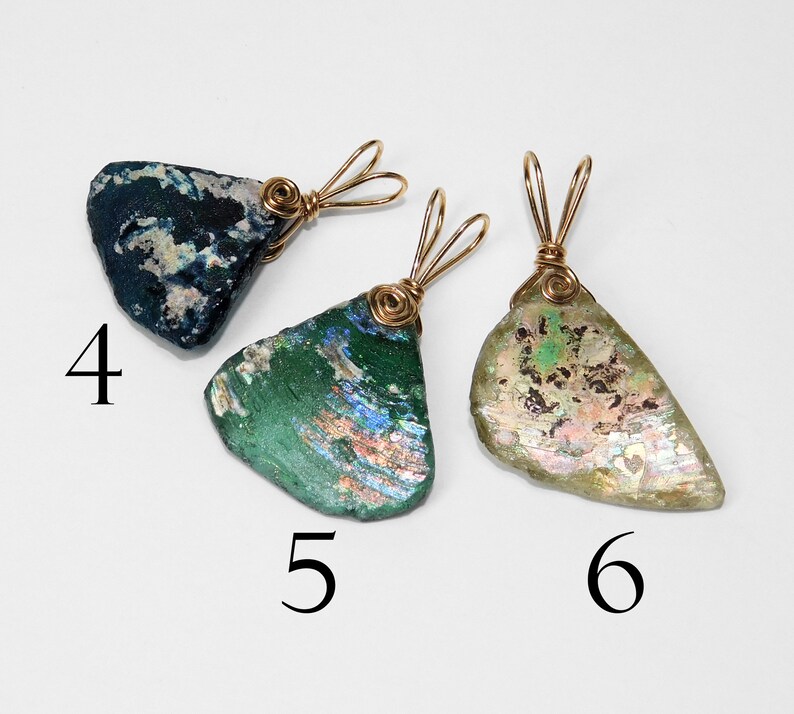 Puede incluir: Tres colgantes hechos de vidrio antiguo, cada uno con una forma y color &uacute;nicos. Las piezas de vidrio est&aacute;n envueltas con alambre de metal dorado. Los colgantes est&aacute;n numerados 4, 5 y 6.