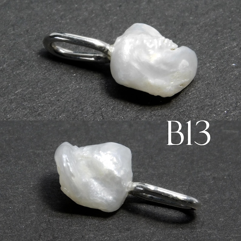 May include: A white, irregularly shaped pearl pendant with a silver-colored loop. The pendant has a natural, organic form and a lustrous surface. The image also includes the text "B13".