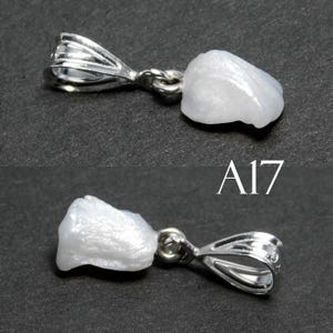 May include: A white pearl pendant with a silver bail. The pearl is irregular in shape and has a smooth, shiny surface. The bail is a simple loop with a slightly textured finish. The pendant is labeled "A17".