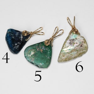 Puede incluir: Tres colgantes &uacute;nicos de formas irregulares. Cada uno es de un color diferente: azul oscuro, verde e iridiscente. Est&aacute;n envueltos con alambre dorado y tienen un lazo para una cadena. Los n&uacute;meros 4, 5 y 6 est&aacute;n impresos en la imagen.