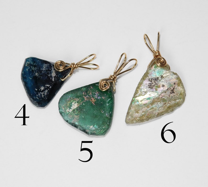 Puede incluir: Tres colgantes &uacute;nicos de formas irregulares. Cada uno es de un color diferente: azul oscuro, verde e iridiscente. Est&aacute;n envueltos con alambre dorado y tienen un lazo para una cadena. Los n&uacute;meros 4, 5 y 6 est&aacute;n impresos en la imagen.