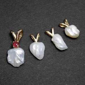 May include: Four white pearl pendants with gold settings. One pendant has a small red gemstone.