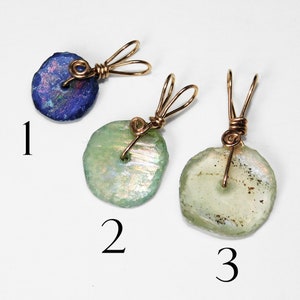 Puede incluir: Tres colgantes hechos a mano con dise&ntilde;os envueltos en alambre. Un colgante es de color azul oscuro, mientras que los otros dos son de color verde claro. Cada colgante tiene una forma irregular &uacute;nica, y el alambre es dorado.
