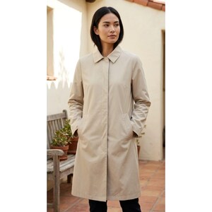 May include: A beige knee-length coat featuring a classic collar, long sleeves, and a concealed front button placket. The coat has a structured silhouette with two side pockets and a smooth, solid-colored fabric finish, providing a clean look.