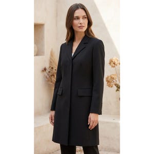 May include: A long-length black coat featuring a notched lapel collar, long sleeves with buttoned cuffs, and two front flap pockets. The coat has a structured fit with a single-breasted front closure and a clean, solid black finish throughout.