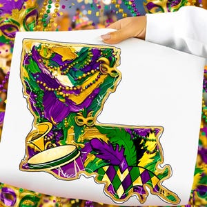 Op de afbeelding: Een kleurrijke illustratie van de staat Louisiana, met Mardi Gras-elementen. Het kunstwerk bevat paarse, groene en gouden kralen, maskers, een trommel en een veer, allemaal omlijnd in goud. De afbeelding wordt tegen een witte achtergrond gehouden.