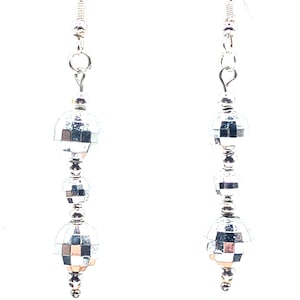 May include: Silver-toned dangle earrings featuring a series of mirrored disco ball-shaped beads. The earrings have a simple hook closure and are designed to catch the light. The beads are arranged in a cascading pattern, creating a glamorous accessory.