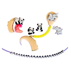 Puede incluir: Aud&iacute;fonos beige y rosa adornados con colgantes de animales, pandas y elefantes. Un cable amarillo conecta los aud&iacute;fonos, y tambi&eacute;n hay un cable morado y blanco.