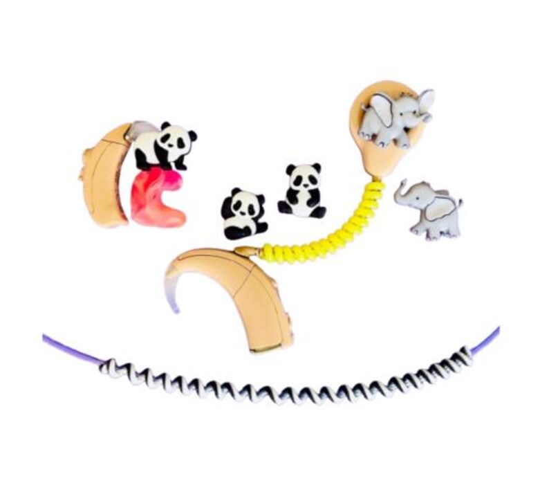 Puede incluir: Aud&iacute;fonos beige y rosa adornados con colgantes de animales, pandas y elefantes. Un cable amarillo conecta los aud&iacute;fonos, y tambi&eacute;n hay un cable morado y blanco.