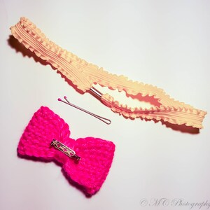 May include: A pink crocheted bow with a silver clasp and a yellow ruffled elastic headband with a silver clip.
