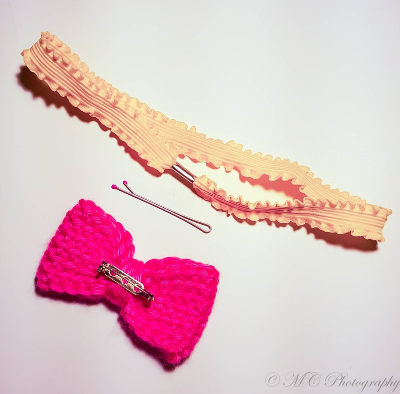 May include: A pink crocheted bow with a silver clasp and a yellow ruffled elastic headband with a silver clip.