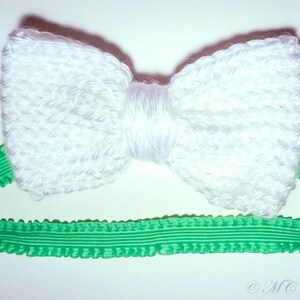 May include: A white crocheted bow headband with a green ruffled elastic band.