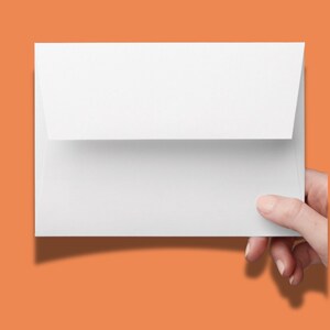 May include: A rectangular white paper envelope with a pointed flap folded down. The envelope is blank and features a smooth, matte texture. It is held horizontally, showcasing a clean, minimalist design suitable for stationery or mailing purposes.