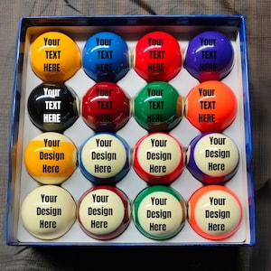 May include: A set of sixteen snooker balls in a blue box. Each ball is a different colour, with the text "Your TEXT HERE" or "Your Design Here" printed on the surface. The balls are arranged in four rows of four.