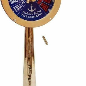 Può includere: Un telegrafo della sala macchine in ottone con manico in legno. Il quadrante è blu con scritte bianche che indicano velocità e direzione. La base è in legno. Un oggetto di arredamento nautico.