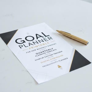 Könnte beinhalten: Ein ausdruckbarer Zielplaner für neue Geschäftsinhaber mit schwarzen und goldenen geometrischen Akzenten, der den Text Goal Planner, Quarterly Planning Template, Startup Success Tracker, Digital Download und Productivity Planner sowie einen goldenen Stift enthält.
