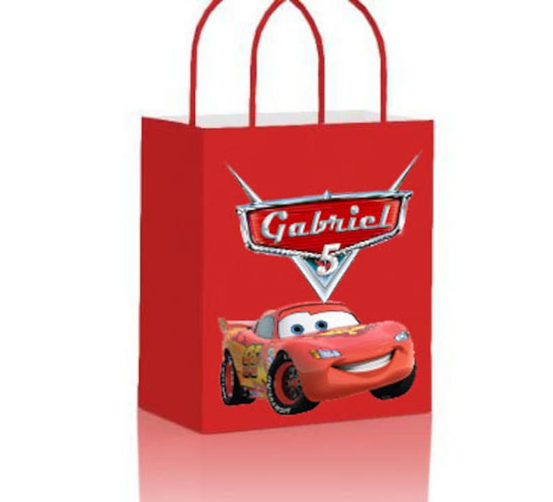 May include: Red and white gift bag with a red race car and the name Gabriel on a silver shield. The car has a number 5 on the side.
