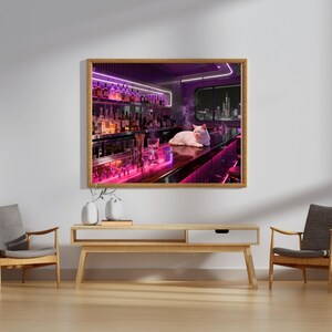 May include: A framed print of a bar scene with a white cat resting on the counter. The bar is illuminated with neon pink and purple lights, and bottles line the shelves. A city skyline is visible through a window.