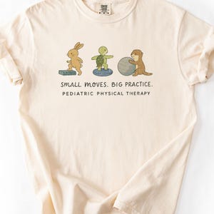 May include: A cream-colored t-shirt featuring a graphic of a rabbit on a step, a turtle on a balance disc, and an otter with an exercise ball. Below the animals, the text reads: SMALL MOVES. BIG PRACTICE. PEDIATRIC PHYSICAL THERAPY.