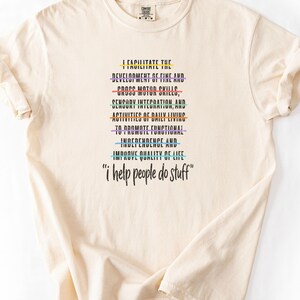 May include: A cream-coloured short-sleeve t-shirt featuring black text that reads: I FACILITATE THE DEVELOPMENT OF FINE AND CROSS MOTOR SKILLS, SENSORY INTEGRATION, AND ACTIVITIES OF DAILY LIVING TO PROMOTE FUNCTIONAL INDEPENDENCE AND IMPROVE QUALITY OF LIFE "i help people do stuff". Each line of text is underlined with a different coloured horizontal line.