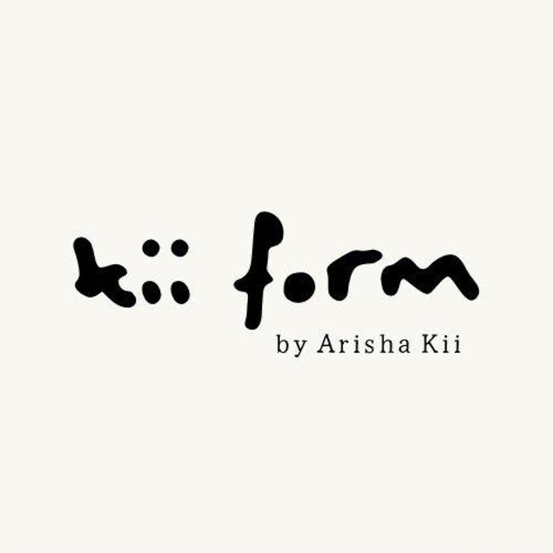 May include: A black logo on a cream background featuring the text kii form in a stylized, hand-drawn font. Below the main text, the words by Arisha Kii appear in a smaller, clean, serif typeface, completing the brand identity graphic design.