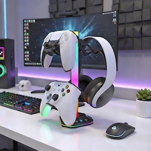 Puede incluir: Soporte para accesorios de juego con un mando blanco de PlayStation 5 y un mando blanco de Xbox. Un par de auriculares blancos y negros cuelgan a un lado. El soporte tiene una base de luz LED colorida y un ratón negro.