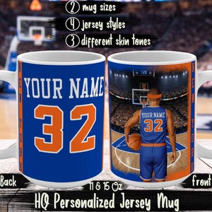 May include: A white ceramic mug with a blue and orange basketball jersey design. The front of the mug features a basketball player with the text "YOUR NAME" and the number "32". The back of the mug has the same design. The mug is available in 11 and 15 oz sizes.