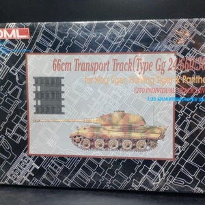 May include: A model kit box featuring a detailed illustration of a camouflaged tank. The box includes text indicating it's a 1:35 quarter scale series with 270 individual track links and a 66cm transport track. The background has a geometric pattern.