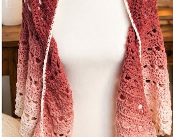 May include: A crochet shawl featuring an ombre color gradient that transitions from a deep dark red at the top to a light cream at the bottom. The garment has an openwork stitch pattern and a solid white crocheted border along the front edges.
