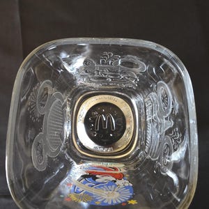 May include: Clear glass square bowl with etched designs and a Mickey Mouse graphic. The center features a gold-rimmed emblem with the McDonald's logo and the year 2000.