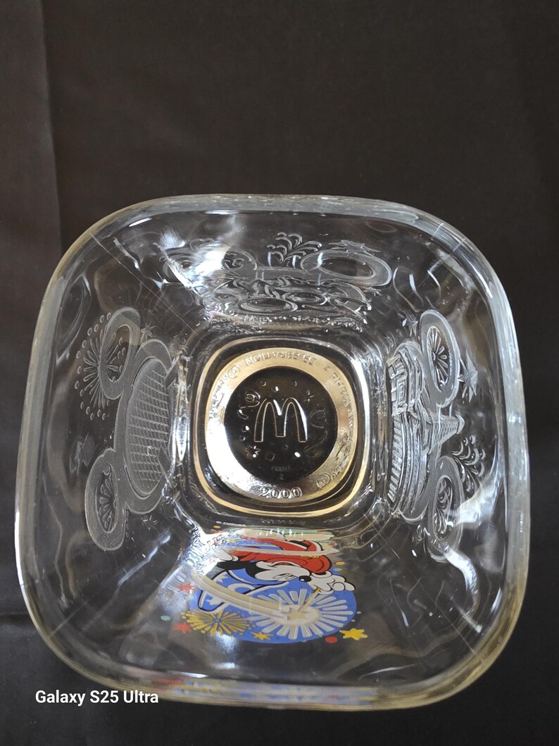 May include: Clear glass square bowl with etched designs and a Mickey Mouse graphic. The center features a gold-rimmed emblem with the McDonald's logo and the year 2000.