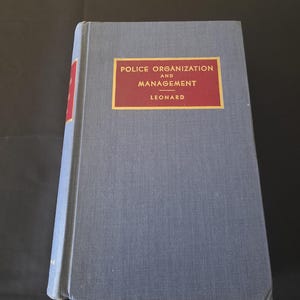 Libro con copertina rigida del 1951 sull'organizzazione e la gestione della polizia, di V.A. Leonard, un testo di riferimento per l'amministrazione di polizia.