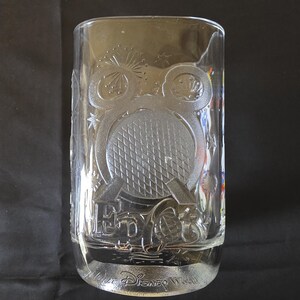 May include: Clear glass tumbler with embossed design featuring a Mickey Mouse head, a tennis ball, and the text "EPCOT" and "Disney World". The glass has a rectangular shape and is suitable for cold beverages.