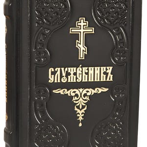 May include: A black book with gold lettering and a gold cross. The cover features ornate embossed designs and the Cyrillic text "СЛУЖЕБНИКЪ". The book has a textured appearance and a classic, religious theme.