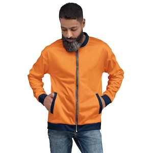 May include: Orange bomber jacket with a black zipper, navy blue trim on the collar, cuffs, and hem. The jacket has two front pockets and is made of a smooth fabric. The jacket is worn by a person.