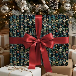 Könnte beinhalten: Ein quadratisches Geschenkpaket in dunklem Papier mit einem wiederkehrenden Muster aus bunten Nussknackern, Weihnachtskugeln und Stechpalmenblättern. Das Paket ist mit einem breiten, glatten, tiefroten Satinband zu einer großen Schleife gebunden.