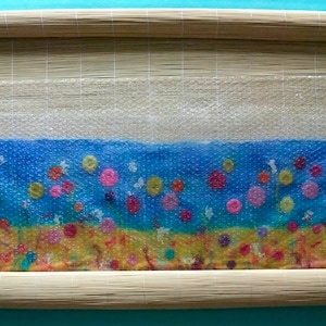 A process image from the PDF tutorial showing the felt being rolled in a rolling mat.  The mat is only half rolled up to show the work inside the mat