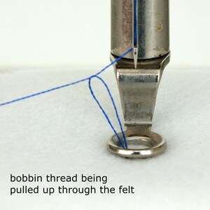 This photo is from the free motion machine embroidery section of the tutorial and shows the bobbin thread being pulled up through the felt in preparation for beginning to stitch
