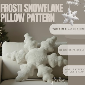 Może przedstawiać: Duża, biała poduszka w kształcie płatka śniegu o teksturowanej powierzchni, eksponowana na białej sofie. Obraz zawiera tekst "FROSTI SNOWFLAKE PILLOW PATTERN", "TWO SIZES: LARGE & MINI" i "BEGINNER FRIENDLY". Mniejsza ozdoba w kształcie płatka śniegu wisi w tle.